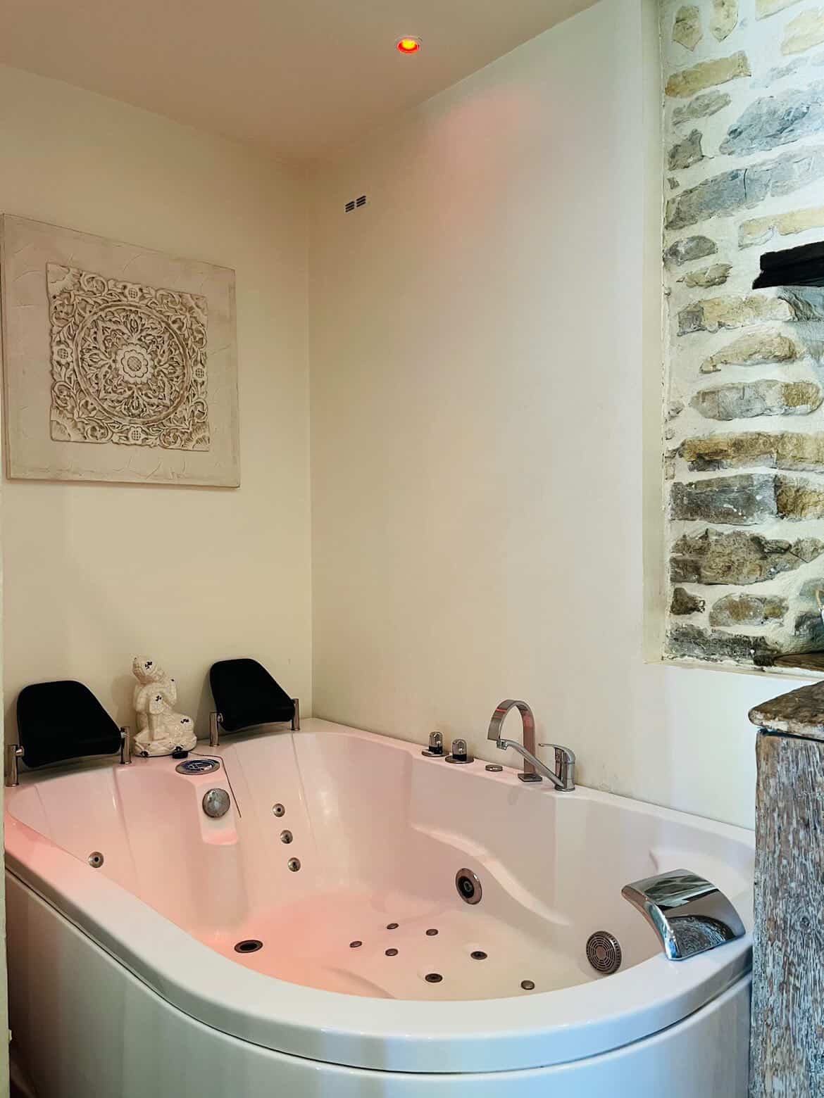 Baignoire balnéo de La Suite contre le mur en pierre apparente