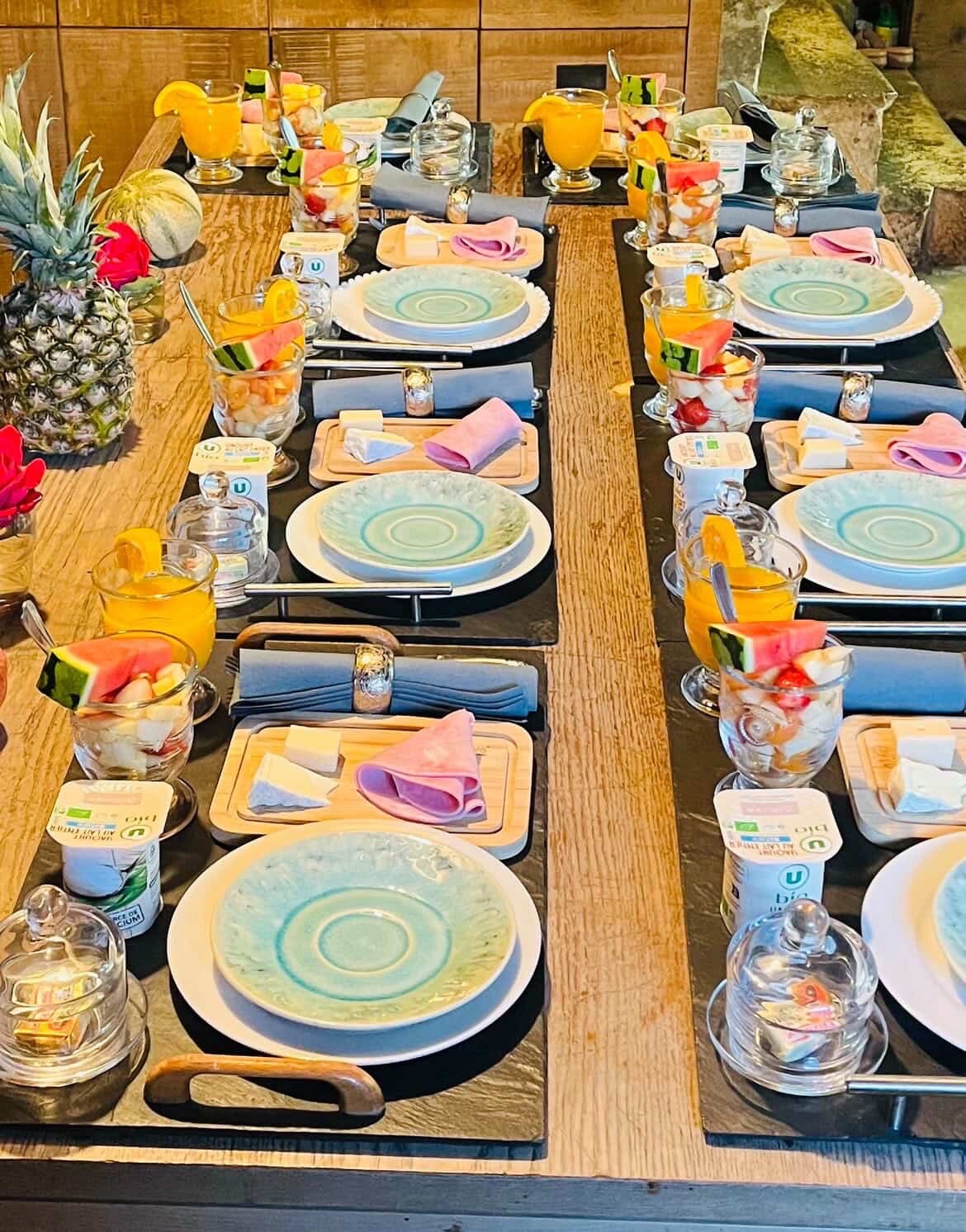 Longue table dressée pour le petit-déjeuner, assiettes turquoise et fruits frais